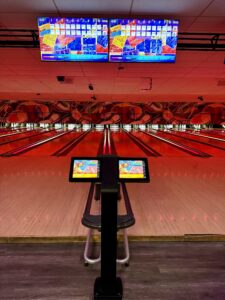 Strikers Bowling – High-Tech Bowling Lanes with Interactive Scoring A vibrant bowling lane at Strikers Bowling in Sunrise, FL, featuring an interactive scoring system, glowing lane lights, and large digital scoreboards