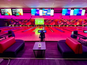 VIP Bowling Experience with Lounge Seating at Strikers Bowling A stylish and modern bowling lane at Strikers Bowling in Sunrise, FL, featuring glowing lane lights, comfortable lounge seating, and interactive scoreboards.