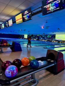 Strikers Bowling – Exciting Games & Neon Alley Experience Best Bowling in Sunrise FL with vibrant lighting, colorful bowling balls, and digital scoreboards displaying game information at Strikers Bowling.