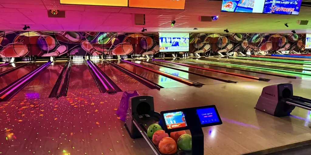 A vibrant bowling alley with neon lighting, multiple lanes, digital scoreboards, and bowling balls ready for play, creating an exciting atmosphere for bowlers.